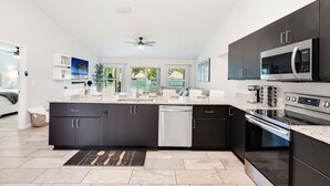 Une cuisine moderne avec des meubles de couleur sombre, des appareils électroménagers en acier inoxydable et un grand îlot central.