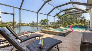 Ein überdachter Außenbereich mit Liegestühlen, einem Pool und Blick auf einen See.