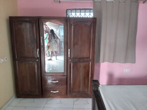 Una stanza con un armadio in legno, un letto e una parete rosa.