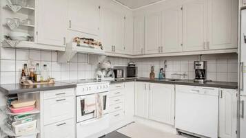 A modern kitchen with white cabinets, a stove, microwave, and a coffee maker.