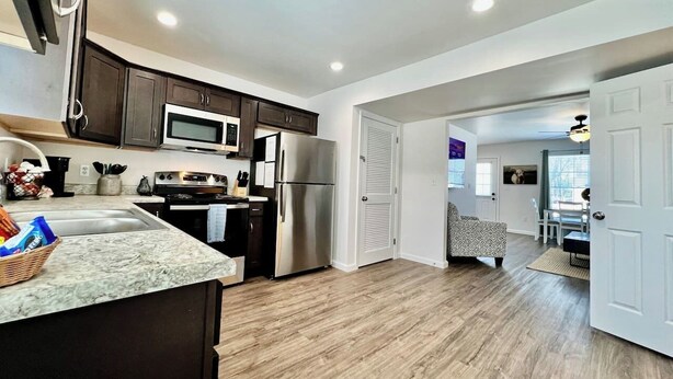 A modern kitchen with dark cabinets, stainless steel appliances, and a marble countertop.