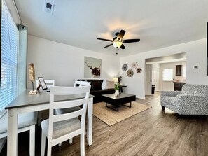 Un salon moderne avec un coin repas, un ventilateur de plafond et un canapé à motifs.
