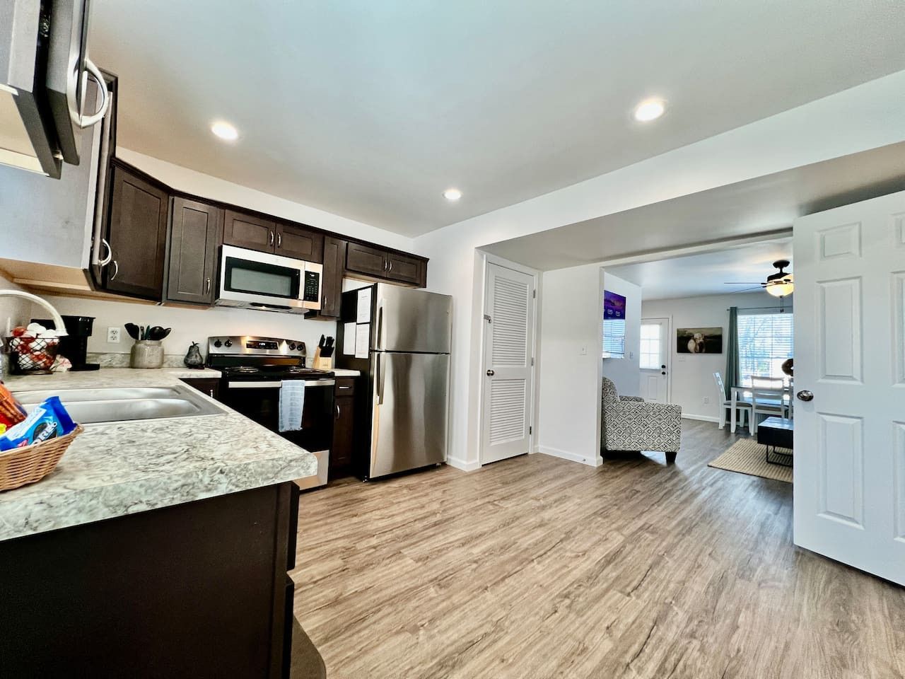 A modern kitchen with dark cabinets, stainless steel appliances, and a marble countertop.