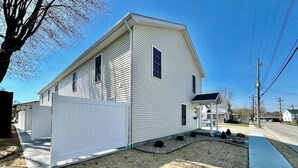 A single-story house with a white exterior, a front porch, and a gravel driveway.