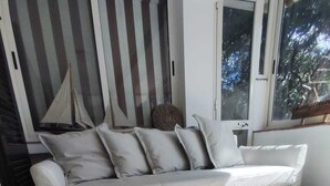 Un salón con sofá, alfombra estampada y ventana con vista a árboles.