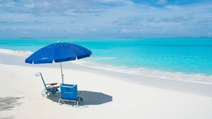 Ranta, jossa on sininen aurinkovarjo ja tuoli.