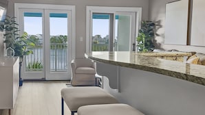 A modern kitchen with a bar area, a ceiling fan, and a view of the water.