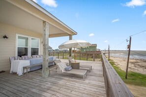 A wooden deck with outdoor seating, a covered area, and a view of the beach and ocean. - Cold Pass Cottage - 3BR, panoramic views (Freeport)