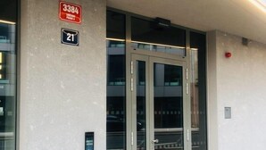 A building entrance with a revolving door, a sign indicating room number 21, and a fire alarm. - Stunning 1-bed Studio (Prague)