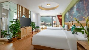 A hotel room with a large bed, a TV, a balcony with a view, and a tropical-themed wall mural. - Tropical Paradise Sapa Hotel (Sa Pa)
