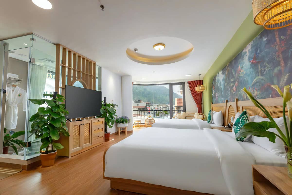 A hotel room with a large bed, a TV, a balcony with a view, and a tropical-themed wall mural.