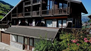 A chalet-style building with a sloped roof, wooden balconies, and large windows. - 50m from ski lifts, 1st floor, terrace, parking, tv, 30m², Arêches-Beaufort (Beaufort)