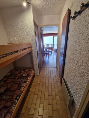 A narrow hallway with a bunk bed on the left and a door leading to a balcony. - 50m from ski slopes, 1st floor, balcony, parking, tv, ski locker, 25m², Les 2 Alpes (Les Deux Alpes)