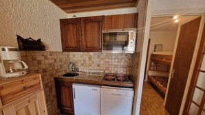 Une cuisine compacte avec des meubles en bois, un four à micro-ondes, un lave-vaisselle et un dosseret carrelé.