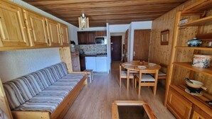 Un espace de vie compact comprenant un canapé, une table à manger et des meubles de rangement en bois.