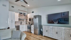 Una cocina moderna con gabinetes blancos, un refrigerador de acero inoxidable y un microondas integrado.