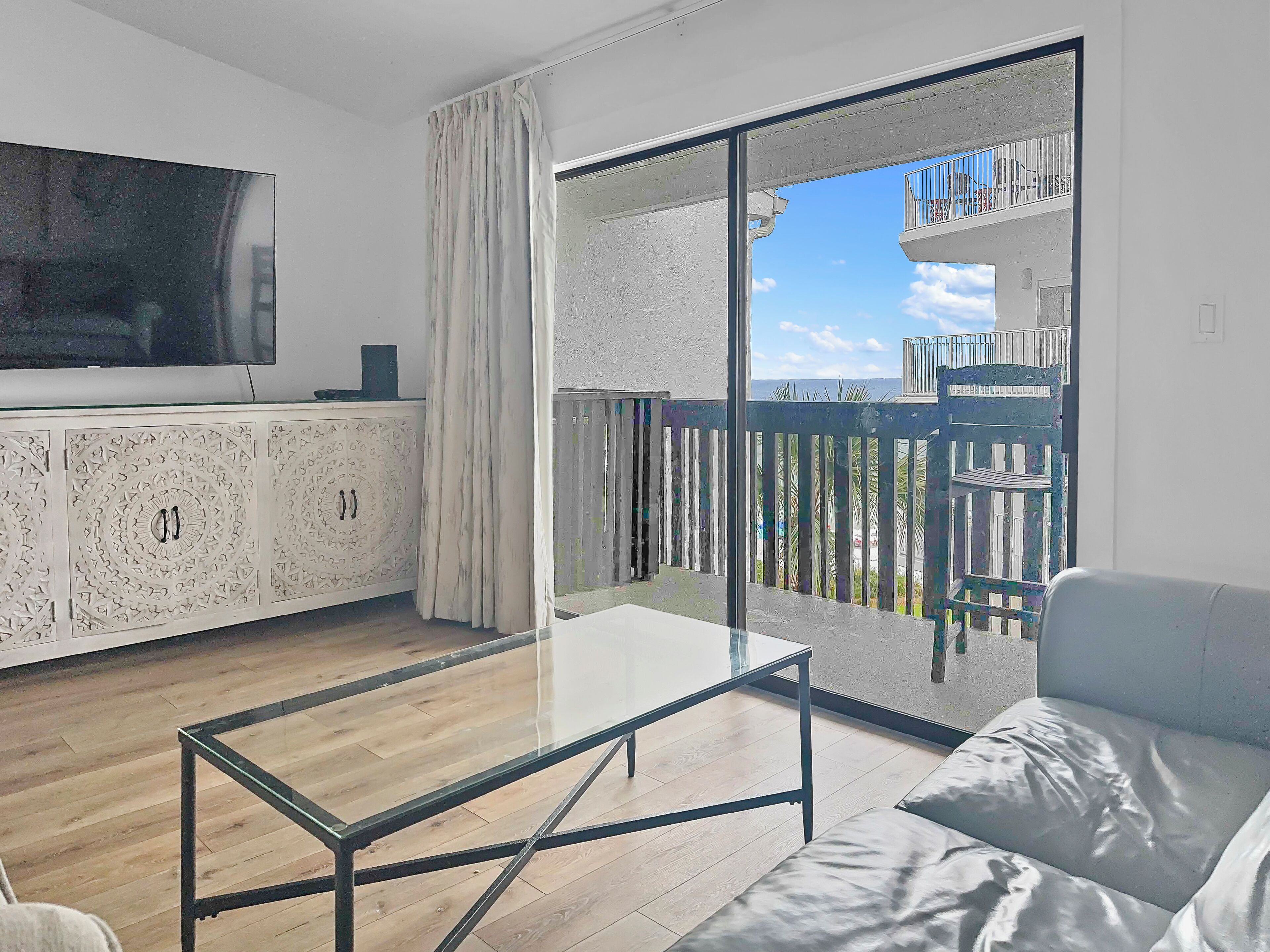 Una sala de estar moderna con una mesa de centro de vidrio, un sofá y un televisor sobre un mueble.