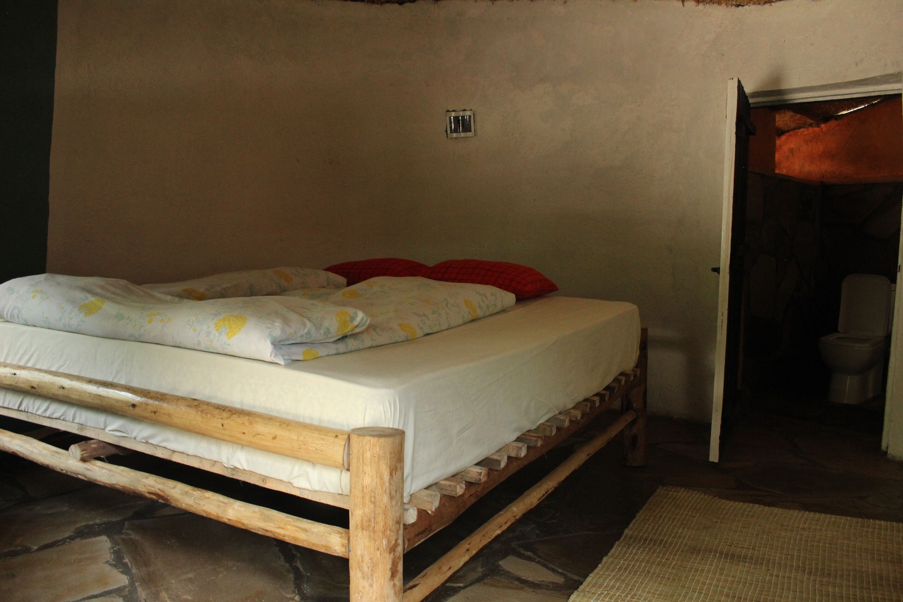 Une pièce avec un lit, une petite fenêtre et une porte donnant sur une salle de bain.
