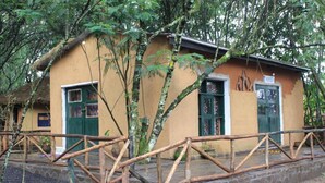 A rustic building with a thatched roof, wooden fence, and a sign indicating it is a guesthouse. - Red Rocks Rwanda - Campsite & Guesthouse (Nkotsi)