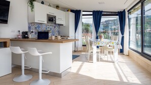 Una cocina moderna con armarios blancos, una isla central, taburetes de bar y una mesa de comedor con sillas.