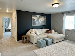 Una sala moderna con un sofá modular, un taburete de madera y una alfombra estampada.