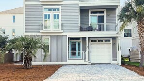 A multi-story residential building with a garage, a driveway, and a landscaped front yard. - Remodeled 5 bedroom house with bikes – walking distance to the beach  (Santa Rosa Beach)