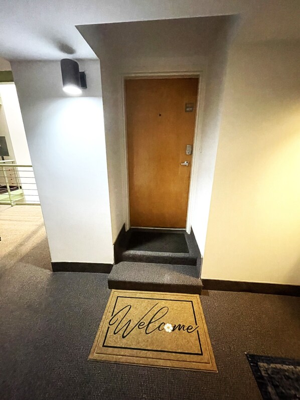 A hotel entrance with a wooden door, a small set of steps, and a welcome mat.