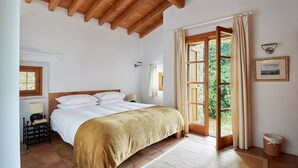 A bedroom with a wooden ceiling, a large bed with white linens, a nightstand with a lamp, and a window with curtains. - Vue Féérique, le Calme de la Campagne (Le Tignet)