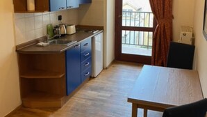 A compact kitchen with blue cabinets, a wooden table, and a window with curtains. - 1 Bed Flat - Sleeps 2 - Pets - Smoking on Terrace (Prague)