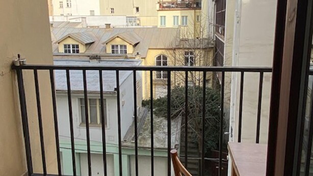 A balcony with a view of neighboring buildings, a table, and a chair. - 1 Bed Flat - Sleeps 2 - Pets - Smoking on Terrace (Prague)