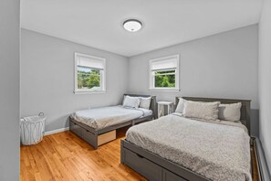 A bedroom with two beds, a ceiling light, and a window with a view of greenery. - Charming 5B Home in Neighborhood (South Burlington)