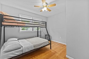 A bunk bed room with a ceiling fan, a window, and a ladder. - Charming 5B Home in Neighborhood (South Burlington)