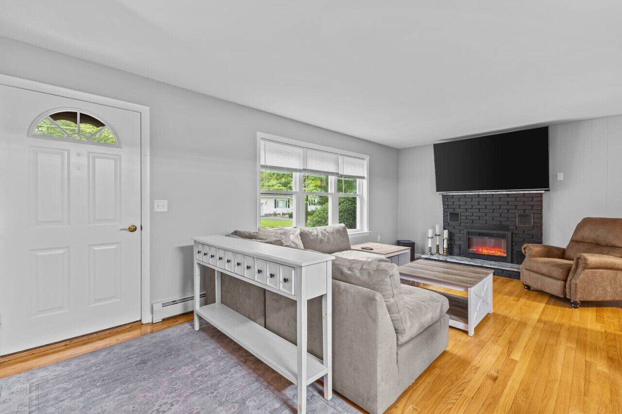 A living room with a fireplace, a sofa, a coffee table, and a TV mounted on the wall.