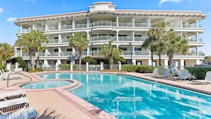 Um hotel com vários andares, piscina e espreguiçadeiras.