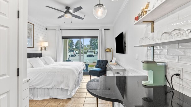 Quarto de hotel com cama, secretária com cafeteira, televisão e vista para a rua.