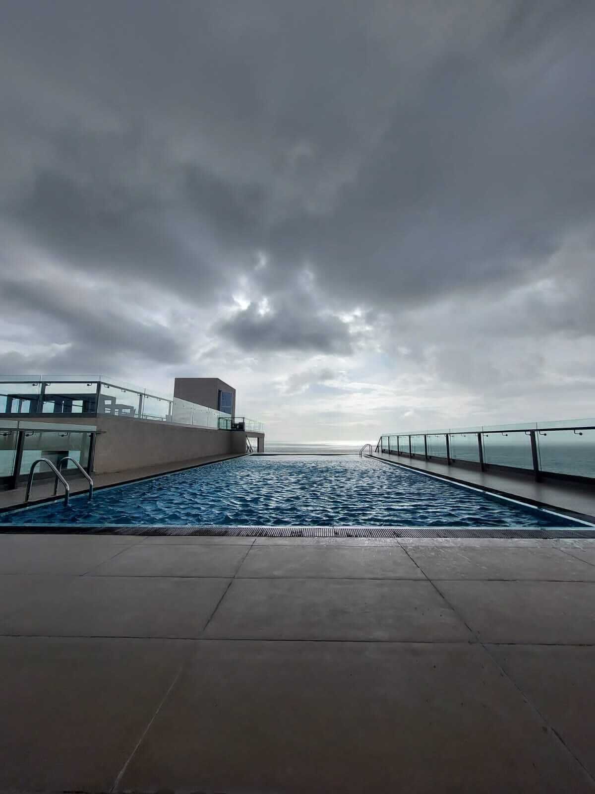 Piscina con vista al mar bajo un cielo nublado.