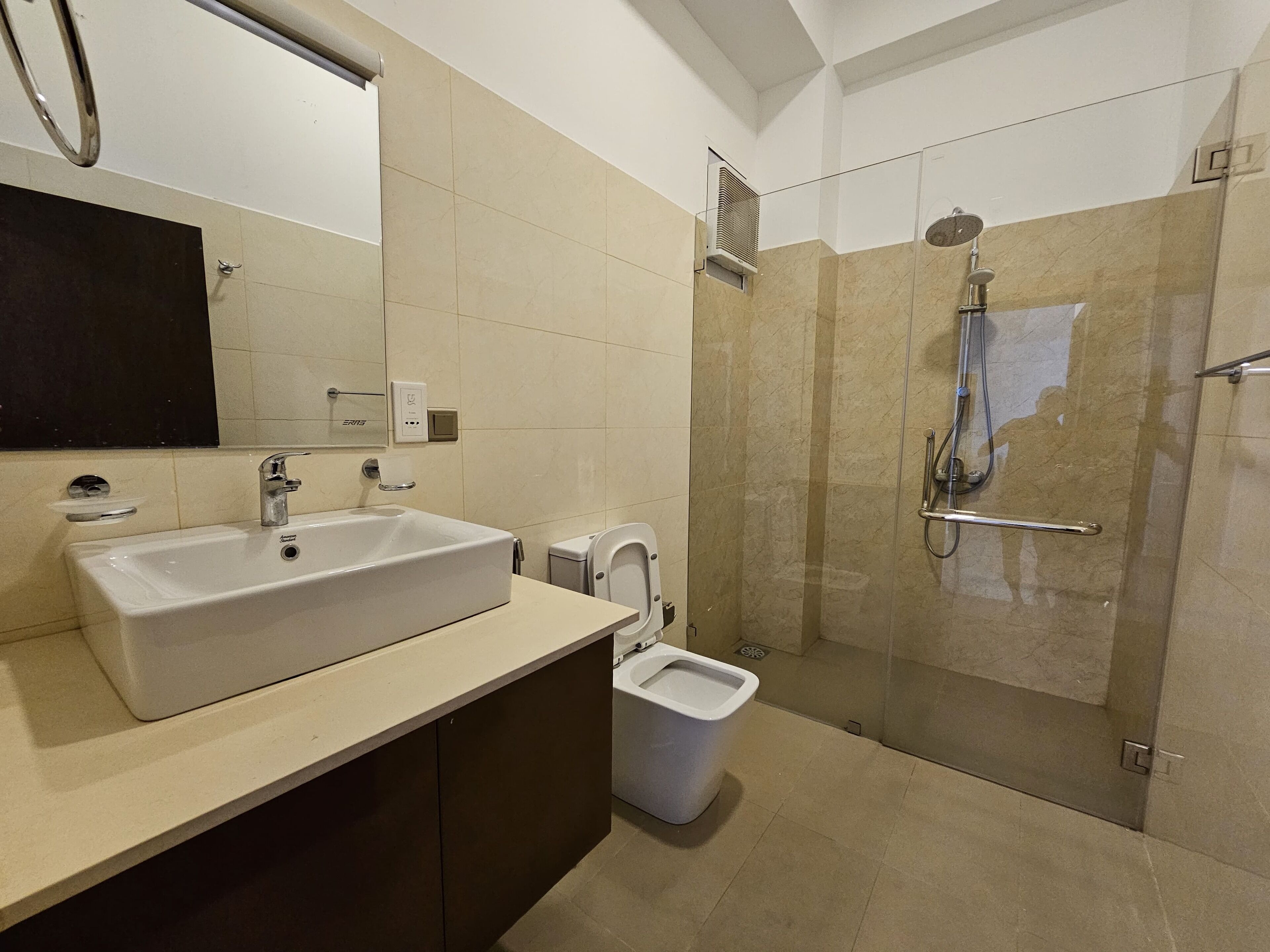 A modern bathroom with a large sink, a toilet, and a glass-enclosed shower area.