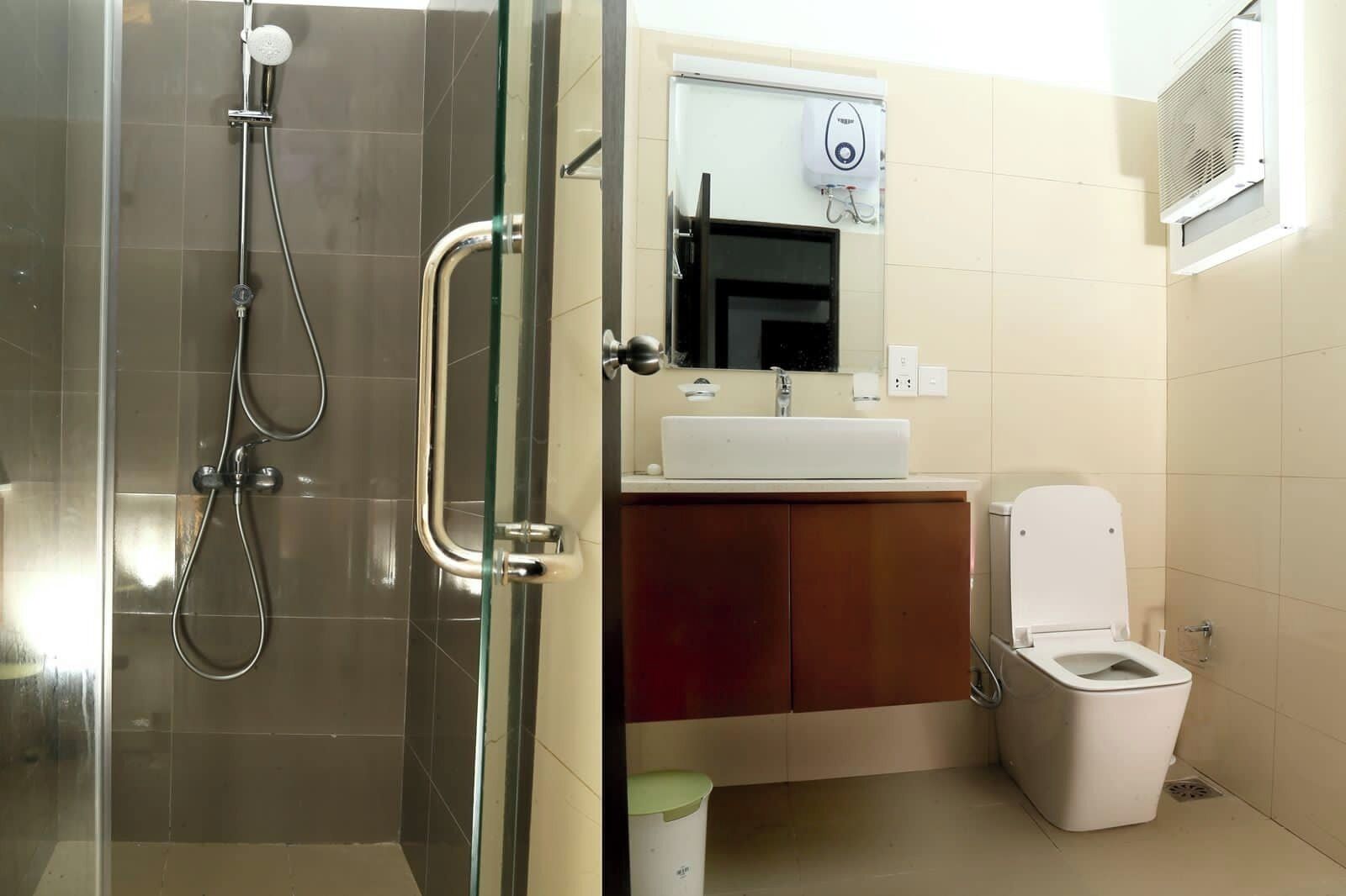 A bathroom with a glass shower enclosure, a white sink, a mirror, and a toilet.