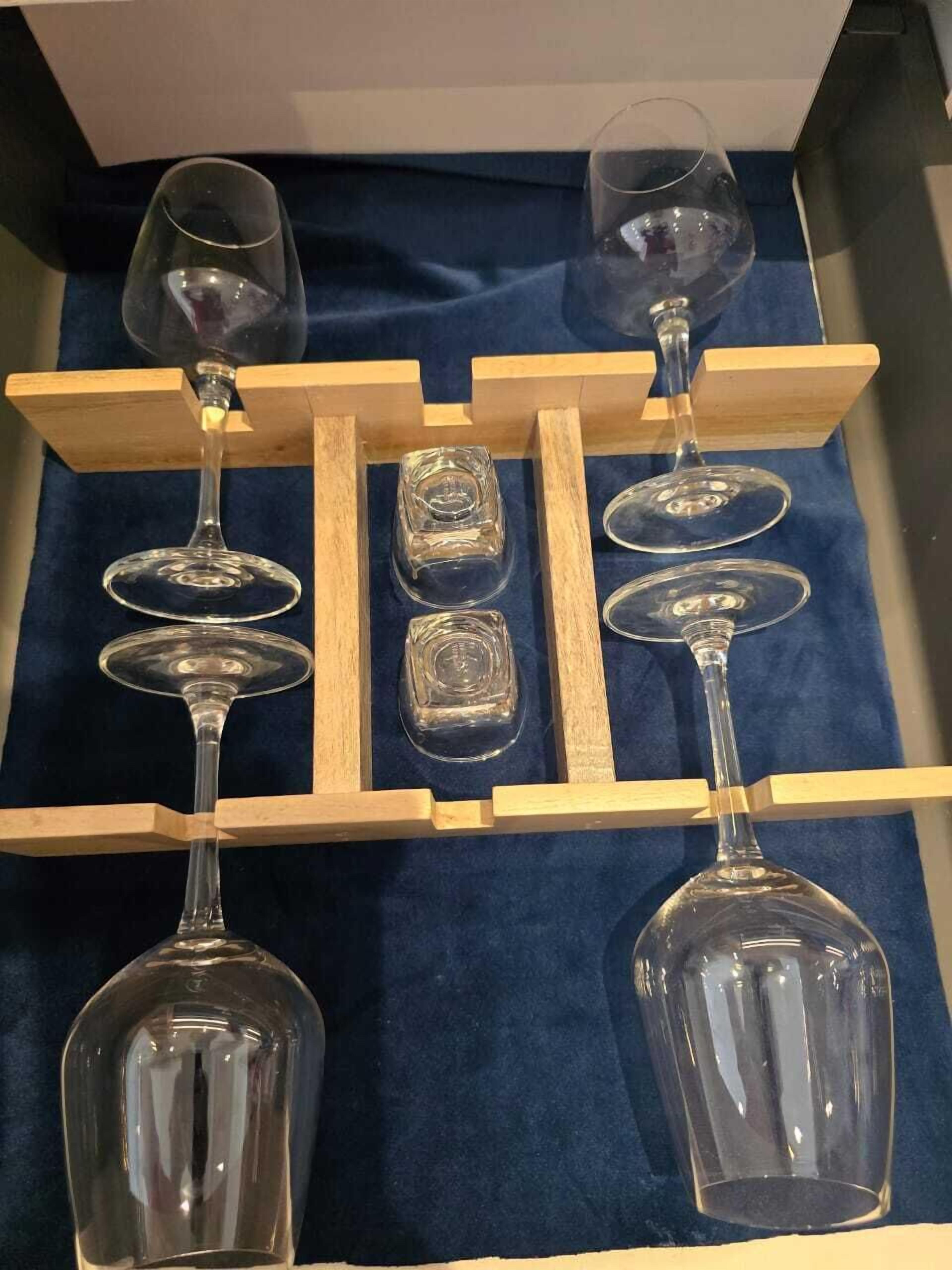 A display of wine glasses and a decanter on a wooden stand against a blue fabric background.