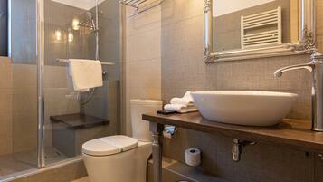 Un bagno moderno con doccia vetrata, un water bianco, un lavandino capiente e uno specchio con cornice decorata.