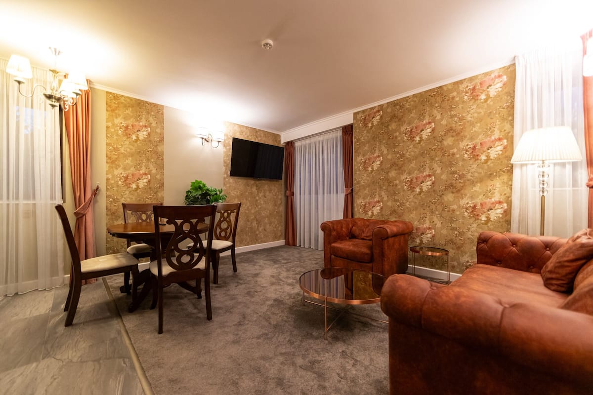 Ein Wohnzimmer mit Esstisch, Stühlen, einer Couch, einem Fernseher und einer Lampe.