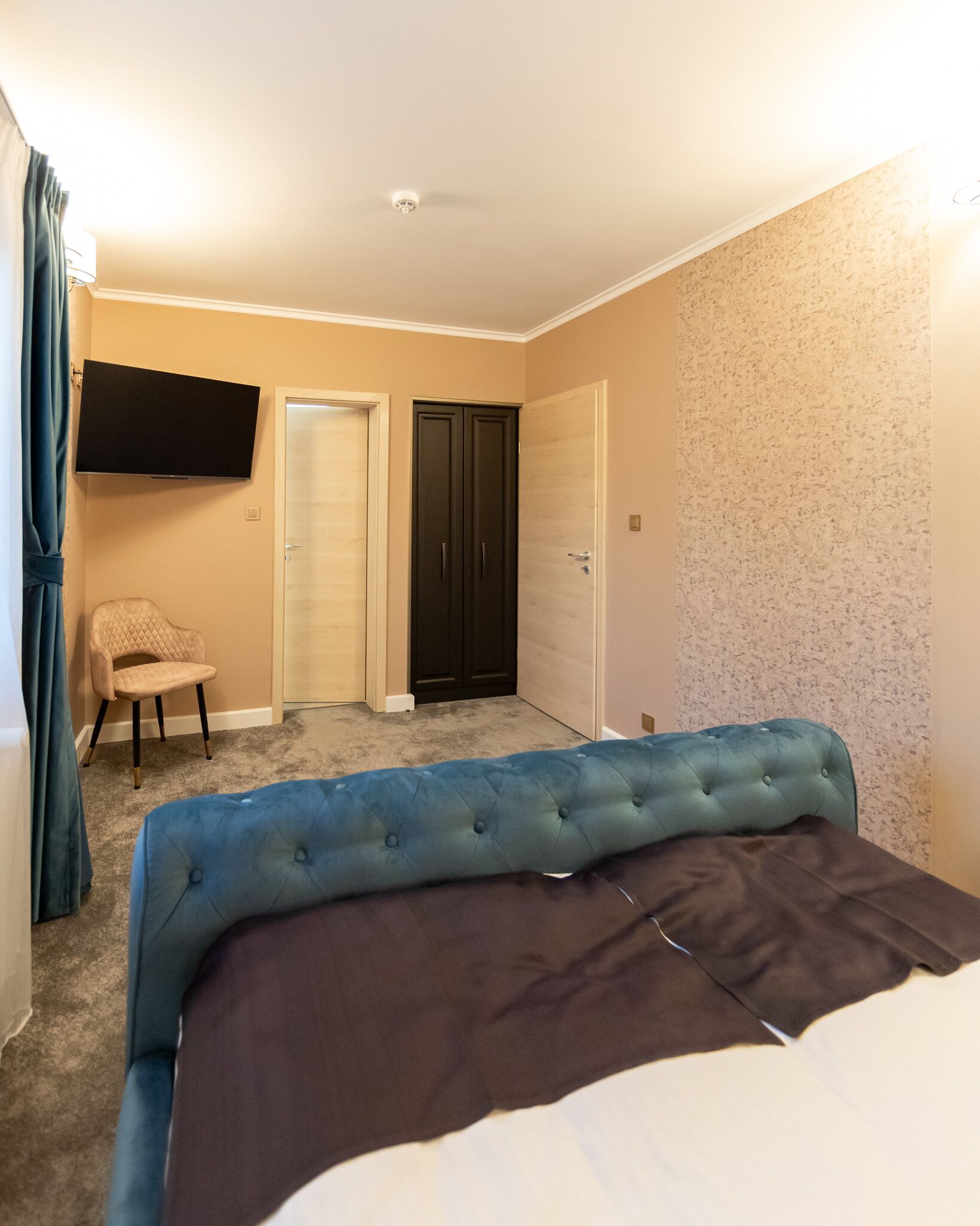 Ein Schlafzimmer mit Bett, Stuhl, Fernseher und zwei Türen.