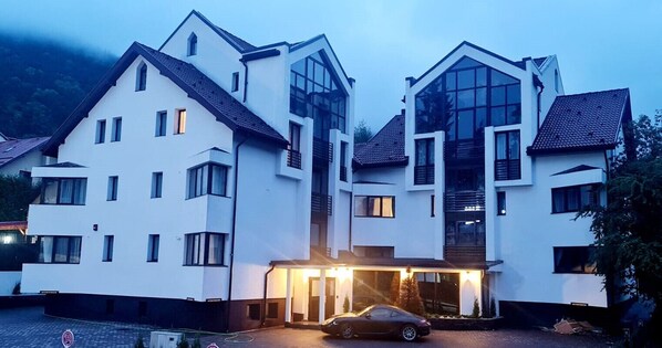 A modern two-story hotel with a prominent entrance and a car parked in front. - Torres Poiana (Brasov)