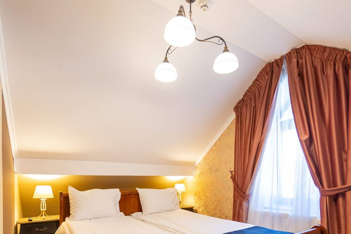 Ein Schlafzimmer mit einem großen Bett, einem Nachttisch, einer Lampe und einer Deckenleuchte.