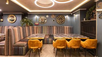 A modern interior with a striped sofa, a marble table, and yellow chairs.
