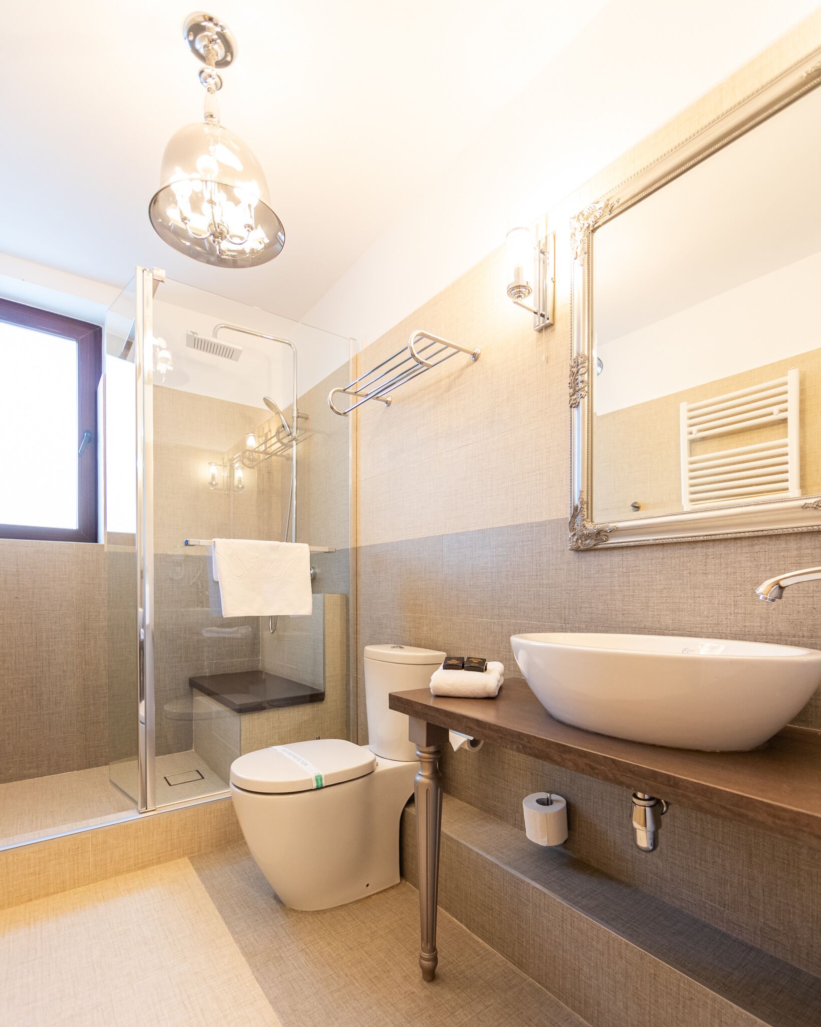 A modern bathroom with a glass shower enclosure, a toilet, a sink with a mirror above it, and a towel rack.