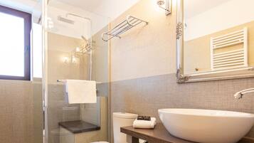 A modern bathroom with a glass shower enclosure, a toilet, a sink with a mirror above it, and a towel rack.