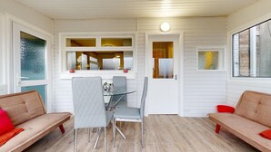 A cozy room with a dining table, two chairs, a sofa, and a window with a view. - Lovely 3 Bedroom House in Dagenham With Parking (Dagenham)