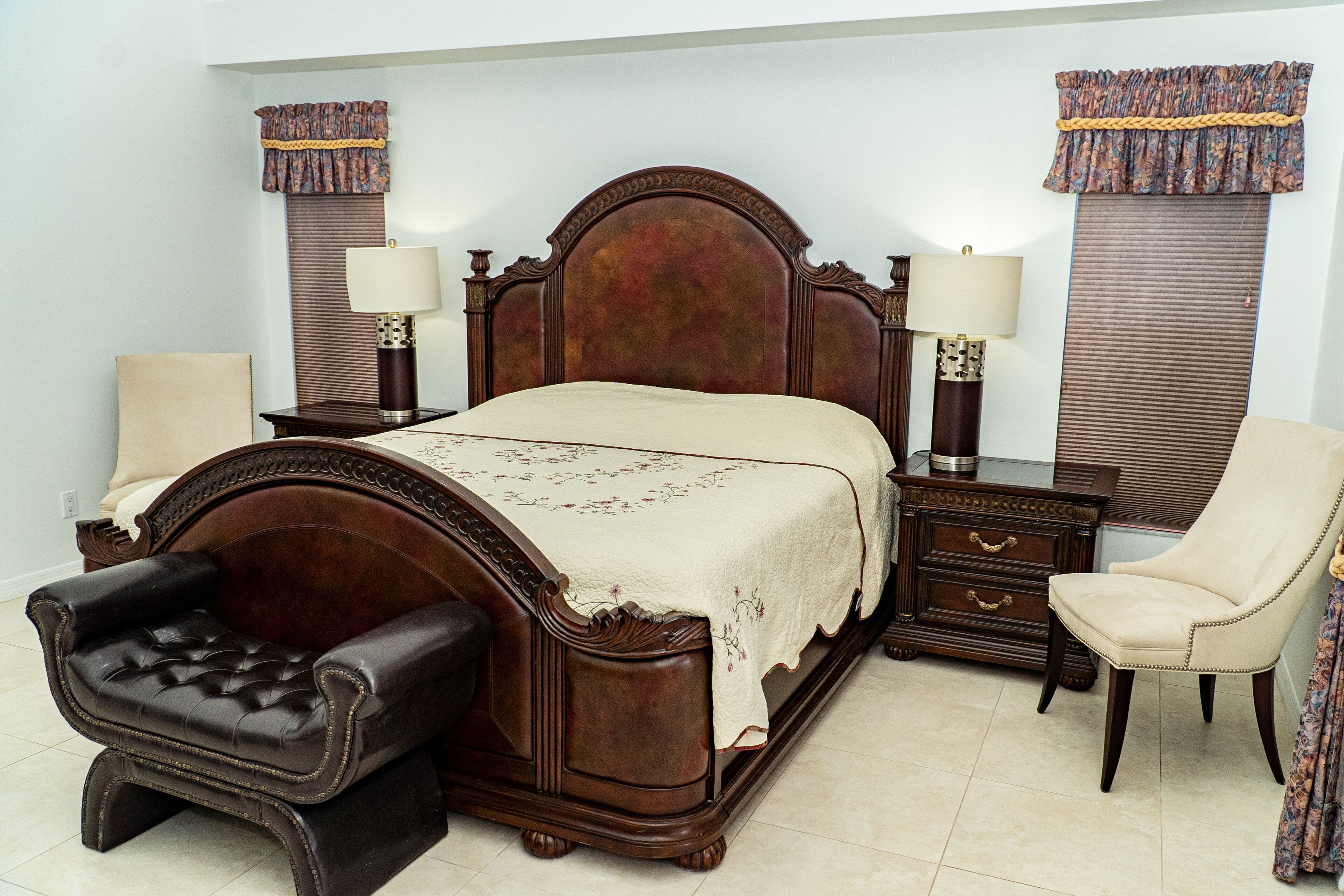 Une chambre à coucher avec un grand lit, deux tables de chevet, une chaise et une commode.