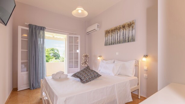 Un dormitorio con cama, ventana con cortinas, aire acondicionado de pared y un cuadro.